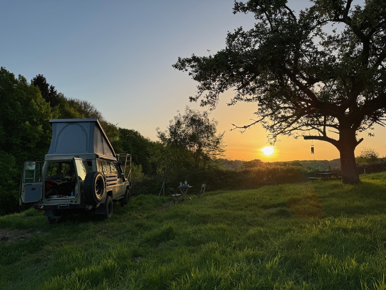 Großer, alter Apfelbaum mit Sonnenaufgang und Campern